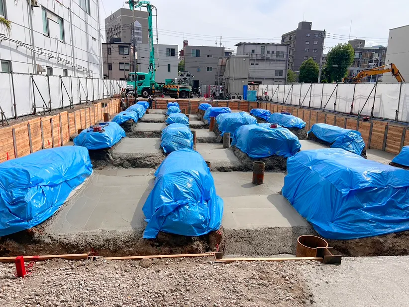 基礎コンクリート（青シート養生された布基礎／ベタ基礎の打設後）